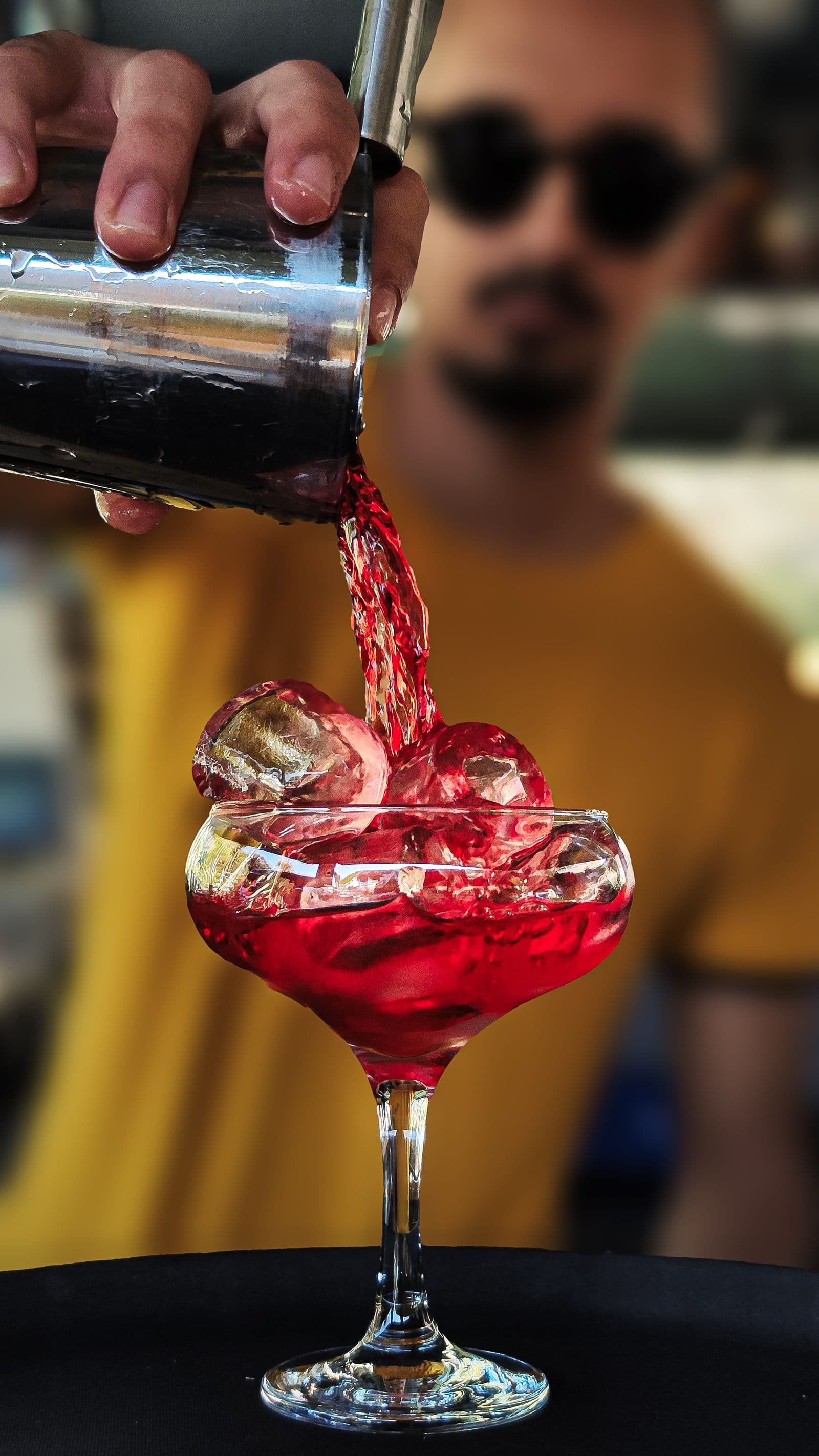 Barmanul Mercury toarnă un cocktail la barul deschis seara