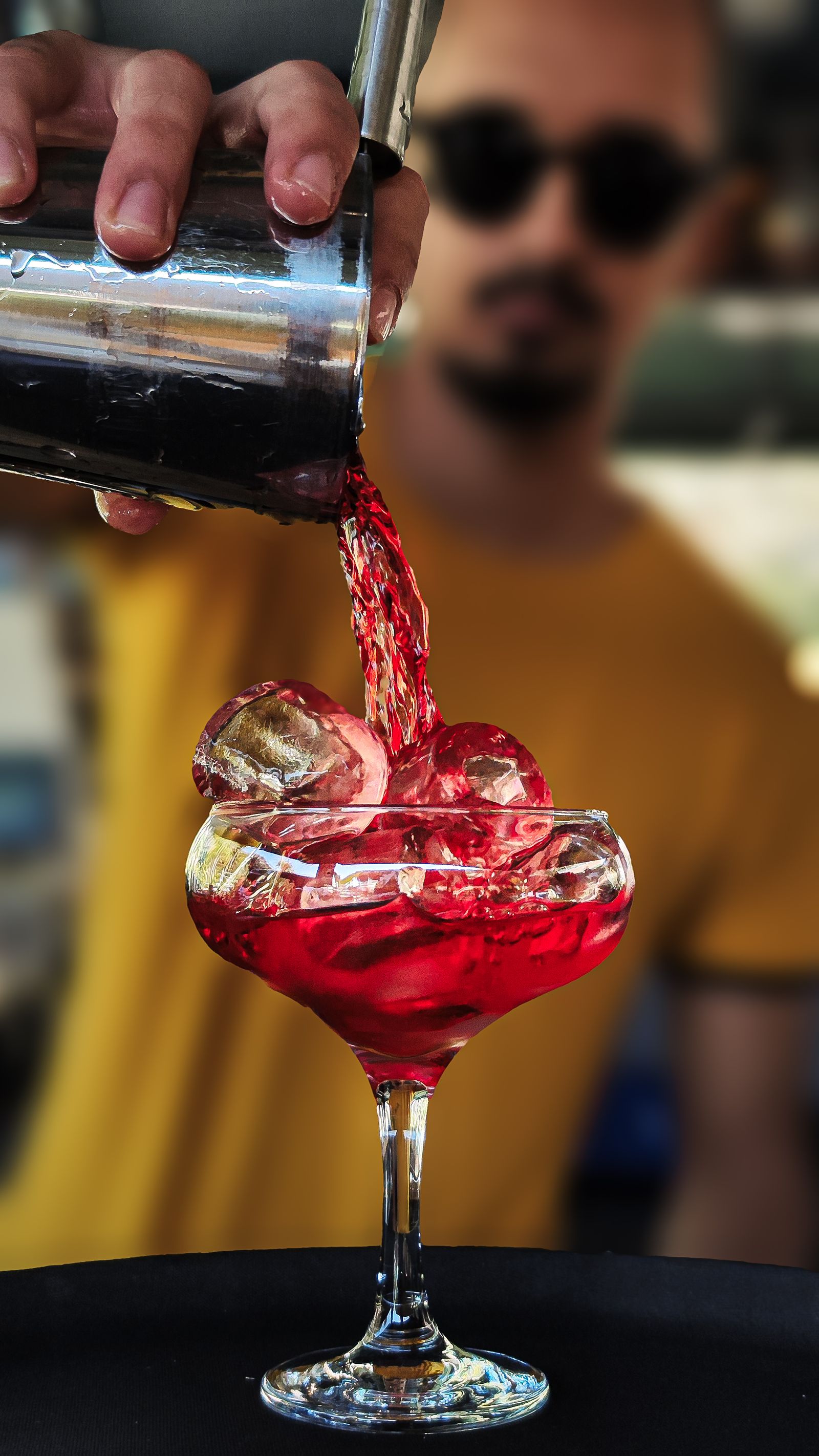 Barmanul Mercury toarnă un cocktail la barul deschis seara