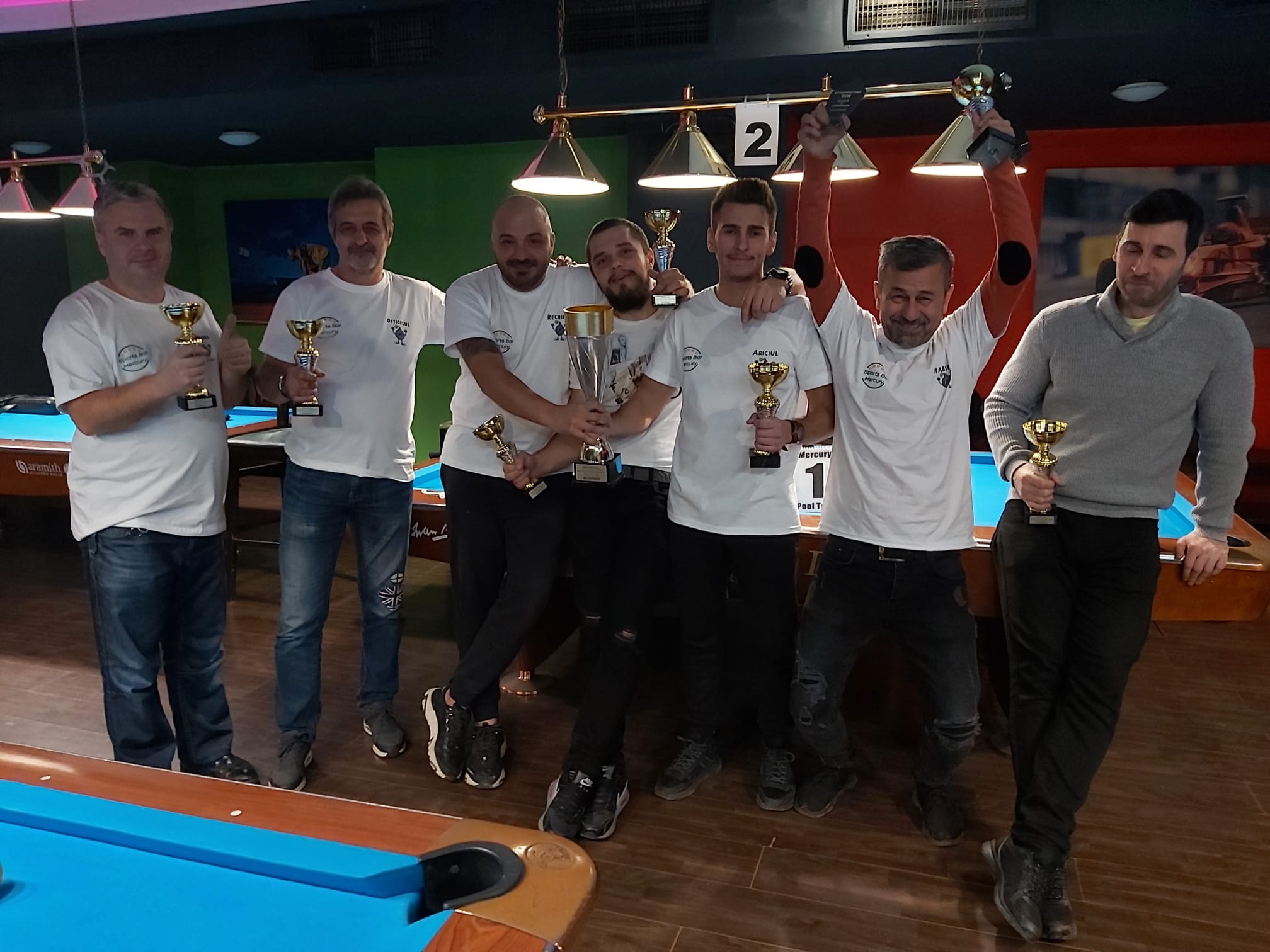 Câștigători Mercury Pool Tour cu trofee, lângă mesele de joc